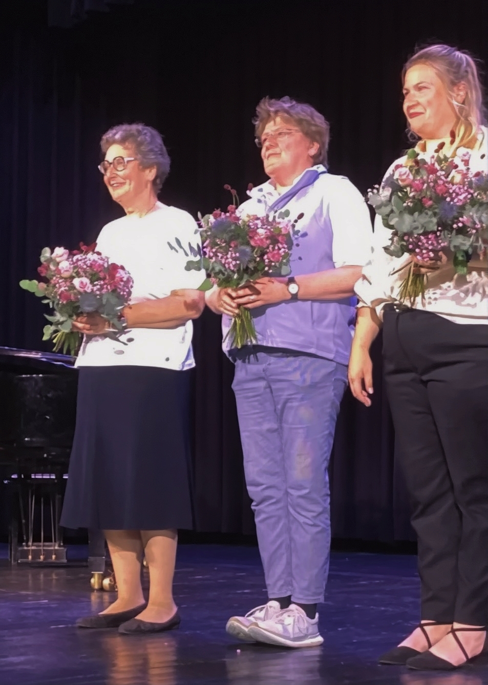 Die drei Musiklehrerinnen auf der Bühne mit ihren Blumensträußen, die ihnen Herr Bigott kurz zuvor überreicht hatte.